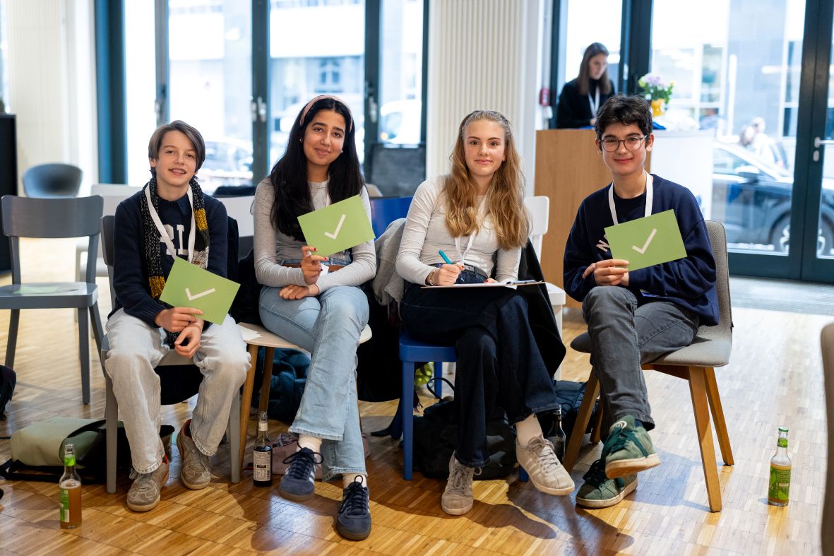 Schülerinnen und Schüler sitzen auf Stühlen